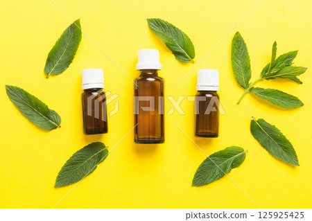 Natural Mint Essential Oil in a Glass Bottle. organic cosmetics with herbal extracts of mint on colored background Natural Mint Essential Oil in a Glass Bottle. organic cosmetics with herbal extracts of mint on colored background 125925425