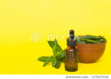 Natural Mint Essential Oil in a Glass Bottle. organic cosmetics with herbal extracts of mint on colored background 125925428