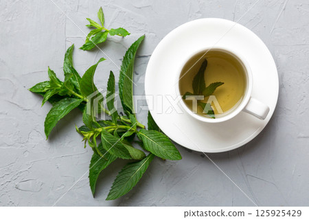 Cup of mint tea on table background. Green tea with fresh mint top view with copy space Cup of mint tea on table background. Green tea with fresh mint top view with copy space 125925429