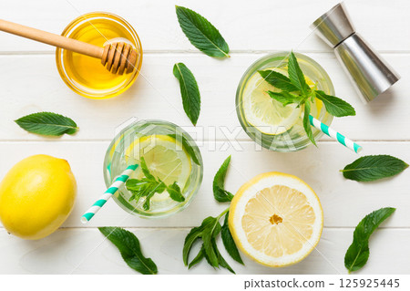 Caipirinha, Mojito cocktail, vodka or soda drink with lime, mint and straw on table background. Refreshing beverage with mint and lime in glass top view flat lay Caipirinha, Mojito cocktail, vodka or soda drink with lime, mint and straw on table background. Refreshing beverage with mint and lime in glass top view flat lay 125925445