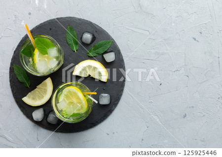 Caipirinha, Mojito cocktail, vodka or soda drink with lime, mint and straw on table background. Refreshing beverage with mint and lime in glass top view flat lay Caipirinha, Mojito cocktail, vodka or soda drink with lime, mint and straw on table background. Refreshing beverage with mint and lime in glass top view flat lay 125925446