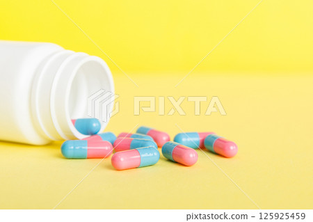 plastic medicine bottle with capsules of pills on colored background. Online pharmacy. Painkiller medicine and antibiotic drug resistance concept. Pharmaceutical industry 125925459