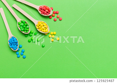 delicious colorful sweet candies on spoon on colored background . Confectionery decor top view with copy space delicious colorful sweet candies on spoon on colored background . Confectionery decor top view with copy space 125925487