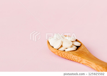 Heap of white pills on colored background. Tablets scattered on a table. Pile of red soft gelatin capsule. Vitamins and dietary supplements concept Heap of white pills on colored background. Tablets scattered on a table. Pile of red soft gelatin capsule. Vitamins and dietary supplements concept 125925502