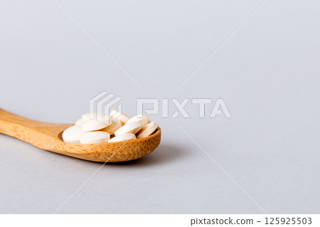 Heap of white pills on colored background. Tablets scattered on a table. Pile of red soft gelatin capsule. Vitamins and dietary supplements concept 125925503