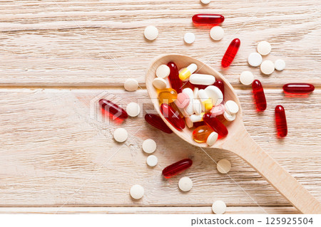 Vitamin capsules in a spoon on a colored background. Pills served as a healthy meal. Red soft gel vitamin supplement capsules on spoon Vitamin capsules in a spoon on a colored background. Pills served as a healthy meal. Red soft gel vitamin supplement capsules on spoon 125925504