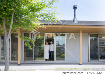 一對夫婦在一棟有綠色和壁爐煙囪的平房的陽台下仰望天空 一對夫婦在一棟有綠色和壁爐煙囪的平房的陽台下仰望天空 125925664