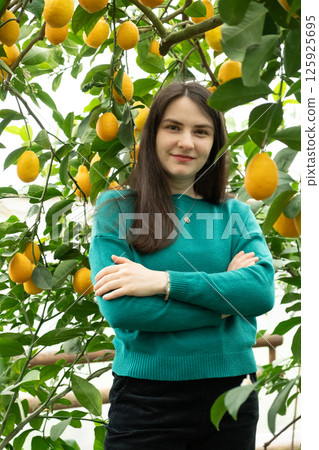 Thoughtful woman with crossed arms on chest in lemon garden Thoughtful woman with crossed arms on chest in lemon garden 125925695