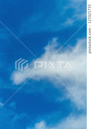 A vertical shot of the sky, the blue of which is partially obscured by a smoke-like cloud, scattering in the wind into small pieces. Environment, protection of nature, atmosphere, air 125925735