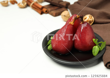 Pears in wine on plate and towel on white background, space for text 125925884