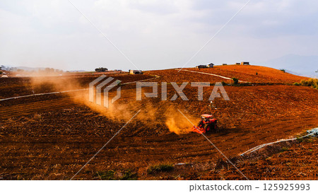Aerial view of tractor plowing in spring. Tractor drives preparing beds for planting seedlings in cultivated soil. Aerial view of tractor plowing in spring. Tractor drives preparing beds for planting seedlings in cultivated soil. 125925993