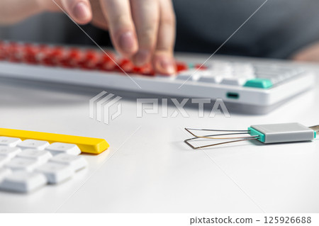 Mechanical keyboard enthusiast using keycap puller tool for custom switch replacement setup Mechanical keyboard enthusiast using keycap puller tool for custom switch replacement setup 125926688