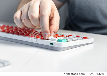 Person assembling mechanical keyboard by pressing white keycap onto red switch component Person assembling mechanical keyboard by pressing white keycap onto red switch component 125926691