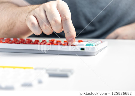 Person pressing white keycap onto red switch during mechanical keyboard customization Person pressing white keycap onto red switch during mechanical keyboard customization 125926692