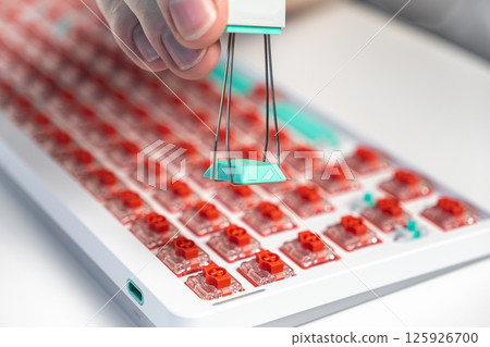 Close-up of hand using wire keycap puller to remove teal key from red switch mechanical board Close-up of hand using wire keycap puller to remove teal key from red switch mechanical board 125926700