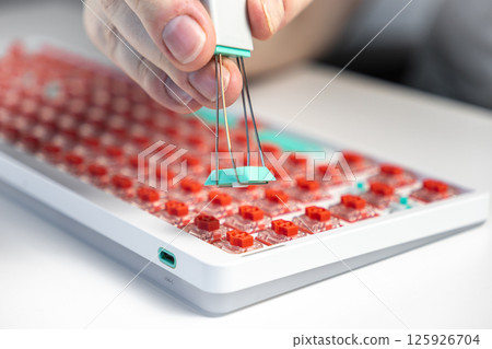 Macro of hand using wire keycap puller to detach teal key from red switch mechanical keyboard Macro of hand using wire keycap puller to detach teal key from red switch mechanical keyboard 125926704