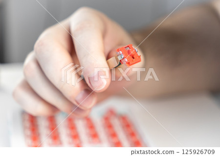 Hand holding red mechanical keyboard switch with tweezers during custom assembly process Hand holding red mechanical keyboard switch with tweezers during custom assembly process 125926709