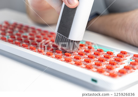 Person using handheld vacuum brush to clean red mechanical keyboard switches during assembly Person using handheld vacuum brush to clean red mechanical keyboard switches during assembly 125926836
