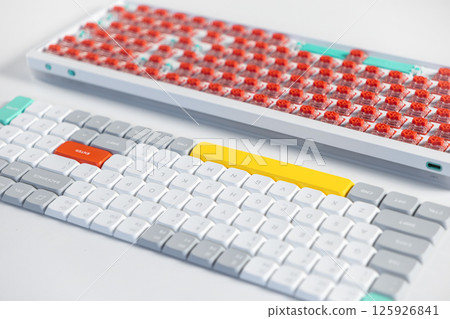 Mechanical keyboard with colorful keycaps placed beside an exposed board with red switches Mechanical keyboard with colorful keycaps placed beside an exposed board with red switches 125926841