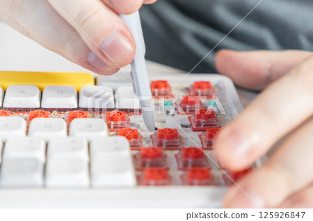 Dirty mechanical keyboard being cleaned with brush tool between switches and keycap spaces Dirty mechanical keyboard being cleaned with brush tool between switches and keycap spaces 125926847