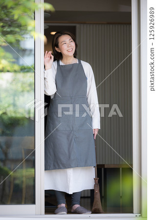 一個女人穿著圍裙，像家庭主婦一樣望著窗外的生活方式和第二人生 125926989