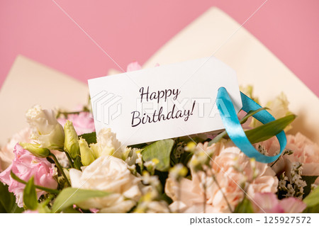 beautiful birthday bouquet with a handwritten "happy birthday" card attached by a blue ribbon, featuring delicate pastel flowers against a soft pink background beautiful birthday bouquet with a handwritten "happy birthday" card attached by a blue ribbon, featuring delicate pastel flowers against a soft pink background 125927572