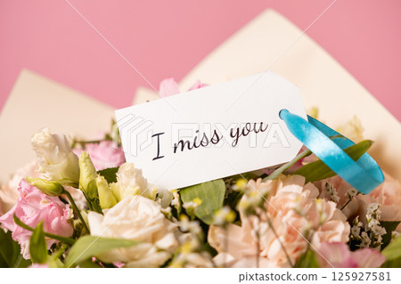 heartfelt bouquet of pastel flowers with a handwritten i miss you message card tied with a blue ribbon, expressing longing and affection on a soft pink background heartfelt bouquet of pastel flowers with a handwritten i miss you message card tied with a blue ribbon, expressing longing and affection on a soft pink background 125927581