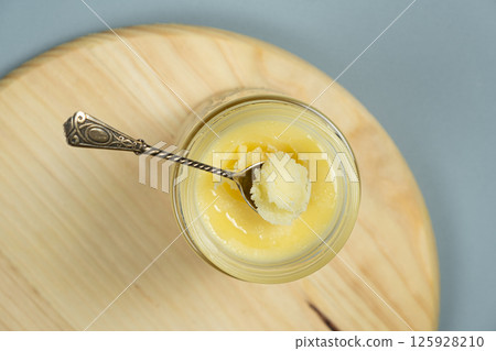 Ghee butter clarified butter jarred in a spoon top view. 125928210