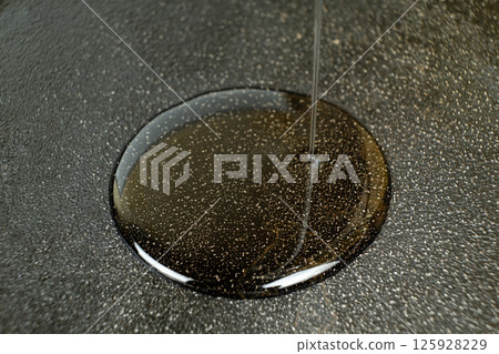 Vegetable oil poured into cast iron pan macro process. Vegetable oil poured into cast iron pan macro process. 125928229