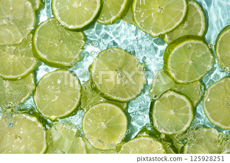 Fresh summer background slices of fresh limes in water, splash of water. 125928251
