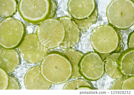 Fresh summer background slices of fresh limes in water, splash of water. Fresh summer background slices of fresh limes in water, splash of water. 125928252
