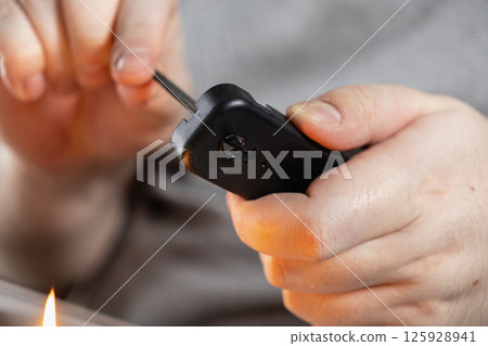 close-up of hands melting plastic with fire to make a hole, diy home project using heated metal tool 125928941