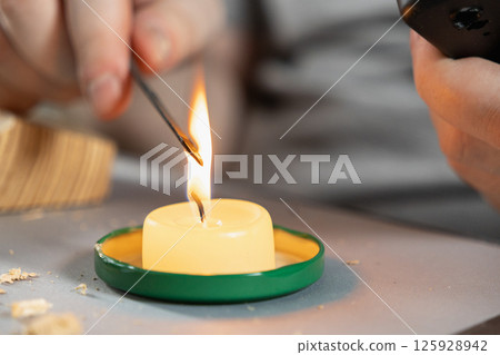 hands carefully heating a metal tool over a candle flame for a diy home repair or crafting project 125928942