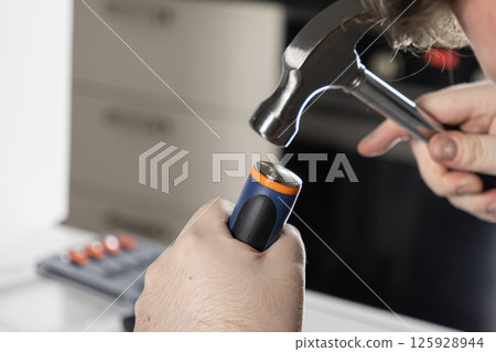 man using a hammer for a diy home repair project, close-up on hands and tools in a workshop setting 125928944