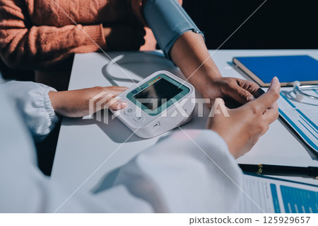 Nurse measuring blood pressure of elderly woman at table, closeup. Assisting senior generation 125929657