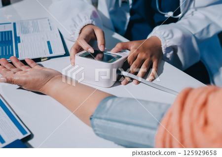 Nurse measuring blood pressure of elderly woman at table, closeup. Assisting senior generation 125929658