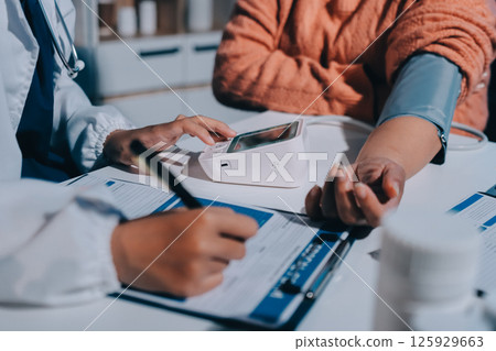 Nurse measuring blood pressure of elderly woman at table, closeup. Assisting senior generation 125929663