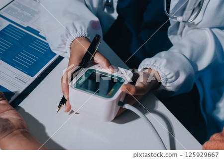 Nurse measuring blood pressure of elderly woman at table, closeup. Assisting senior generation 125929667