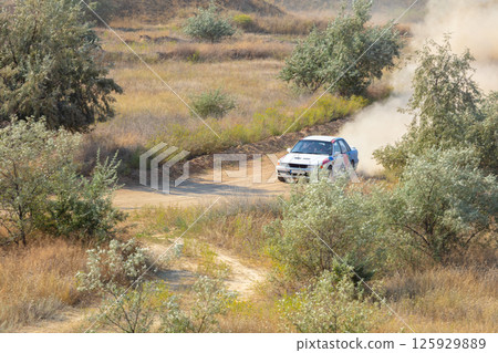 Rally Car Drives along a Dirt Track 125929889