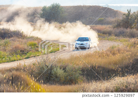 White Sports Car Raises a Cloud of Dust 125929897