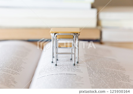 書桌上一本打開的英語書和一張微型課桌學習和學習的形象 125930164