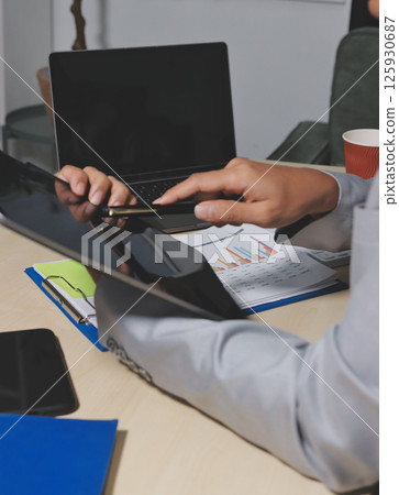 Working from home, Closeup business woman using laptop computer and analyzing financial report. Working from home, Closeup business woman using laptop computer and analyzing financial report. 125930687