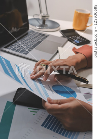 Working from home, Closeup business woman using laptop computer and analyzing financial report. 125930698