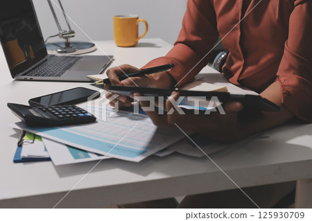 Working from home, Closeup business woman using laptop computer and analyzing financial report. Working from home, Closeup business woman using laptop computer and analyzing financial report. 125930709