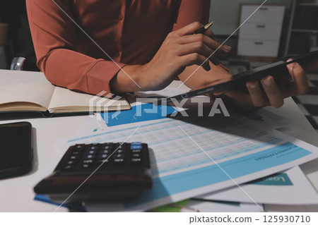 Working from home, Closeup business woman using laptop computer and analyzing financial report. Working from home, Closeup business woman using laptop computer and analyzing financial report. 125930710