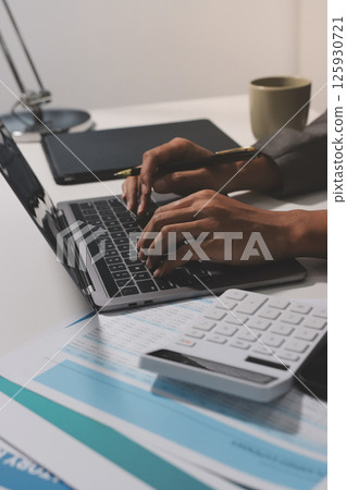 Working from home, Closeup business woman using laptop computer and analyzing financial report. 125930721