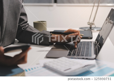 Working from home, Closeup business woman using laptop computer and analyzing financial report. 125930731