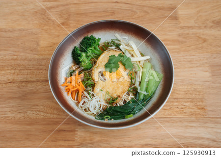 Noodles with deep fried egg and vegetables. Delicious freshly prepared meal, perfect for menus, restaurants, or food delivery concepts. 125930913