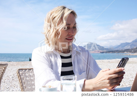 mature woman working outside in caffe on beach coast, lifestyle people concept mature woman working outside in caffe on beach coast, lifestyle people concept 125931486