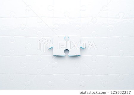 Concept for problem-solving, teamwork, solutions, or missing connections. White jigsaw puzzle on a vibrant blue background with one missing piece. Minimalist composition with copy space. Concept for problem-solving, teamwork, solutions, or missing connections. White jigsaw puzzle on a vibrant blue background with one missing piece. Minimalist composition with copy space. 125932237